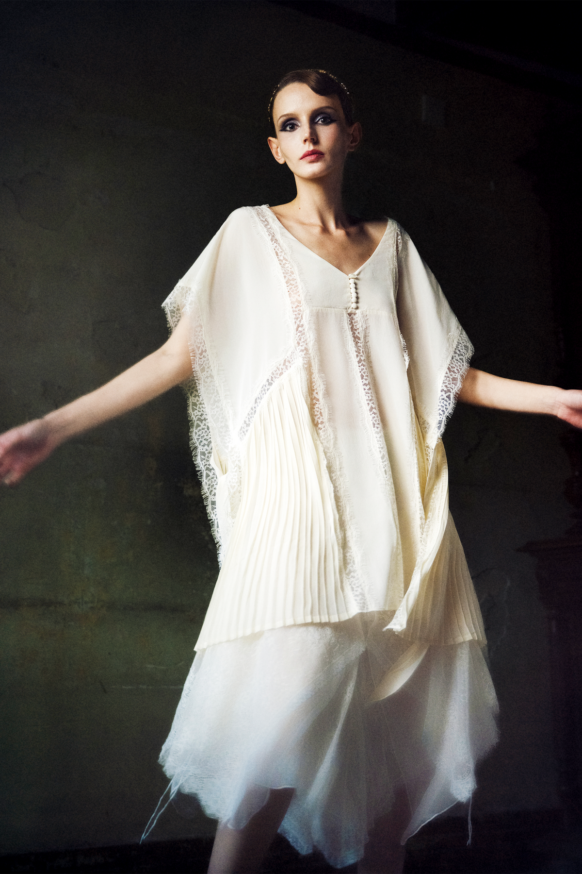 Woman wearing ivory silk kaftan top with lace trim and pleated hem panels