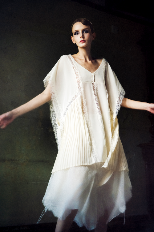 Woman wearing ivory silk kaftan top with lace trim and pleated hem panels