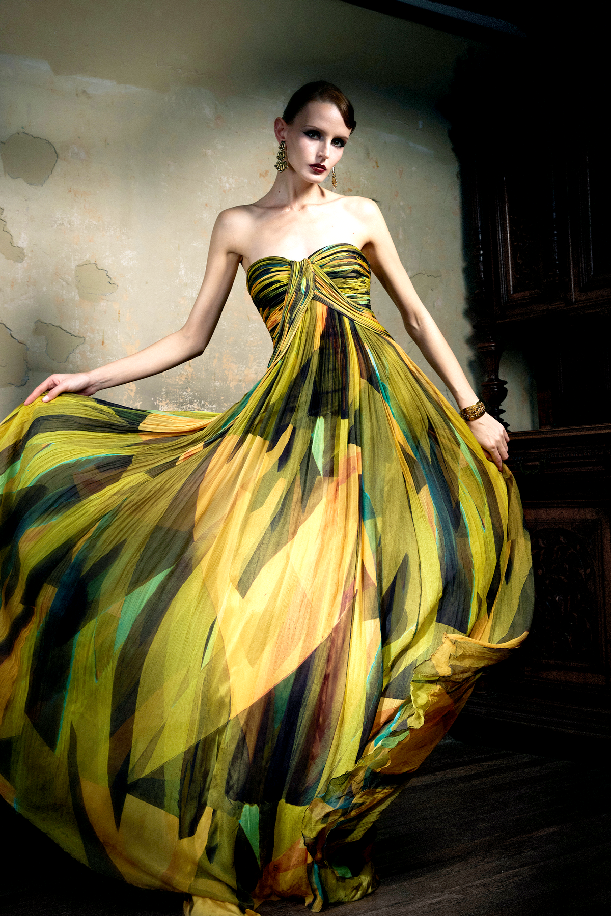 Woman wearing multicolor pleated silk strapless gown with sunset print, full skirt