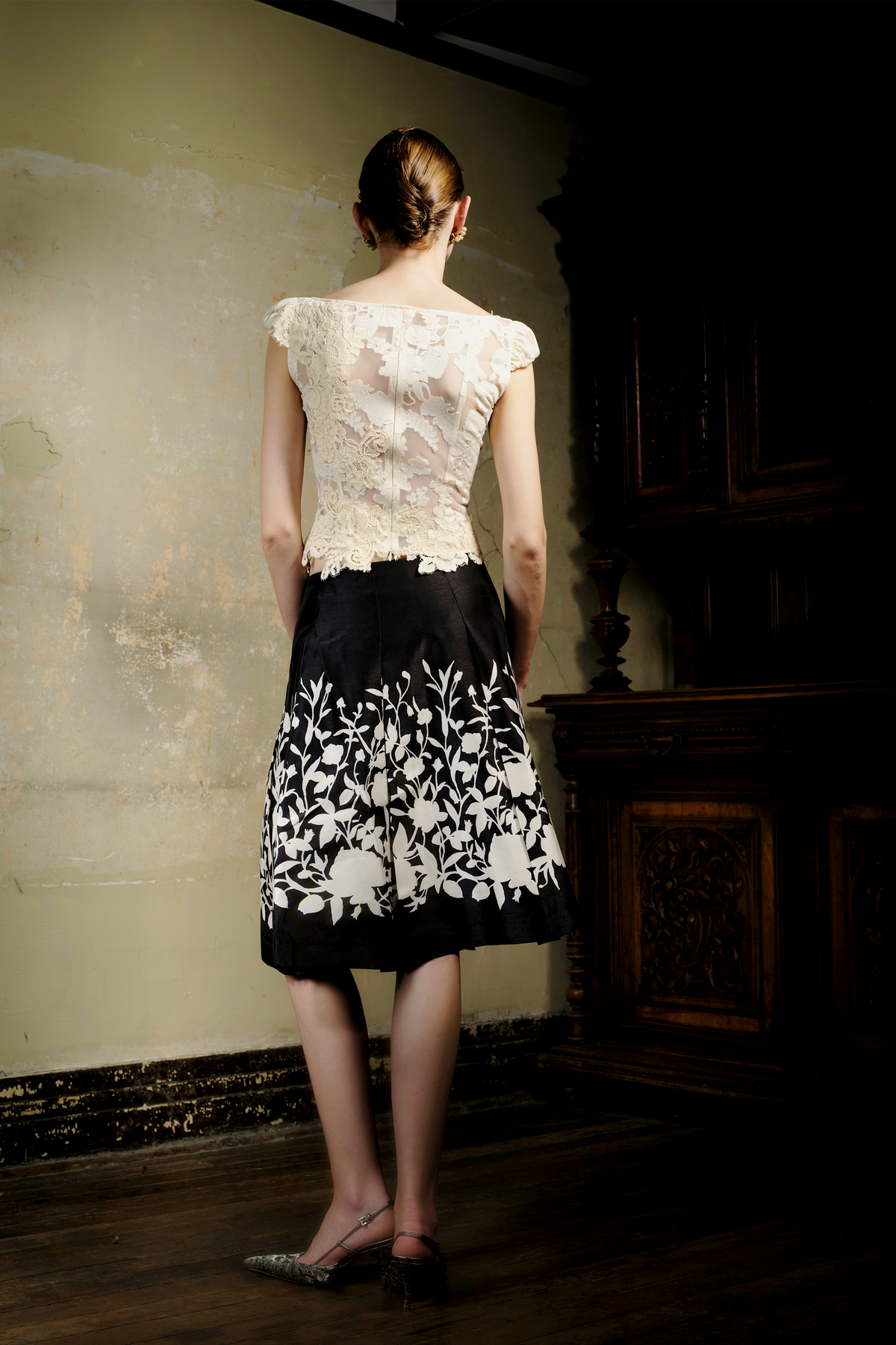 Black A-line pleated skirt with cream floral print at hem, front view