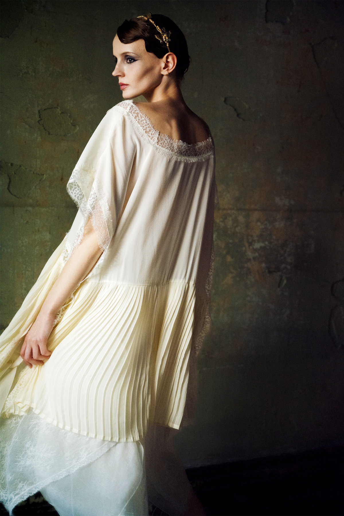 Woman wearing ivory silk kaftan top with lace trim and pleated hem panels
