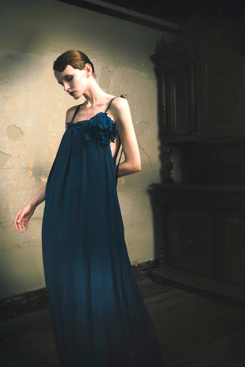 Woman wearing emerald cupro slip dress with handmade frayed flower applique at bust