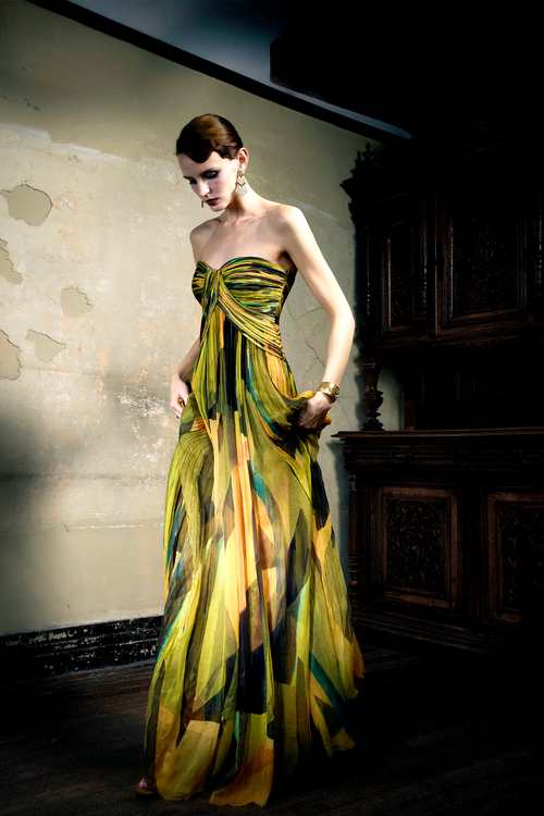 Woman wearing multicolor pleated silk strapless gown with sunset print, full skirt