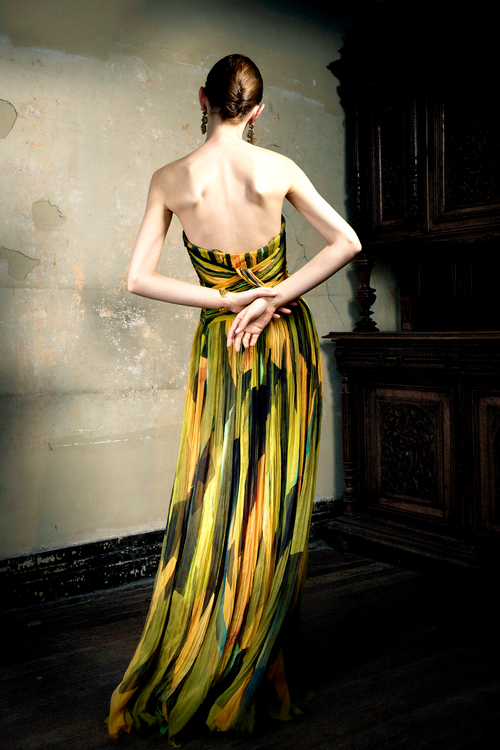 Woman wearing multicolor pleated silk strapless gown with sunset print, full skirt