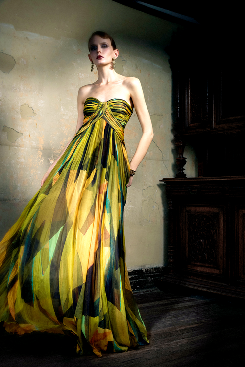 Woman wearing multicolor pleated silk strapless gown with sunset print, full skirt