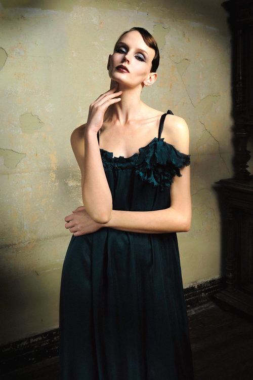 Woman wearing emerald cupro slip dress with handmade frayed flower applique at bust