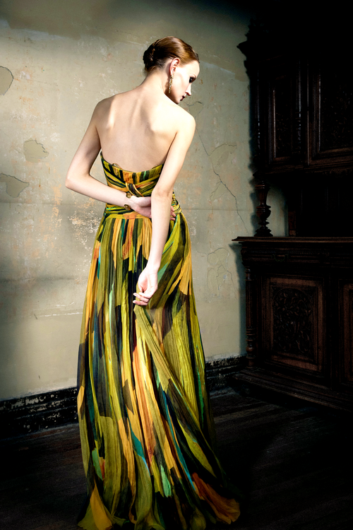 Woman wearing multicolor pleated silk strapless gown with sunset print, full skirt