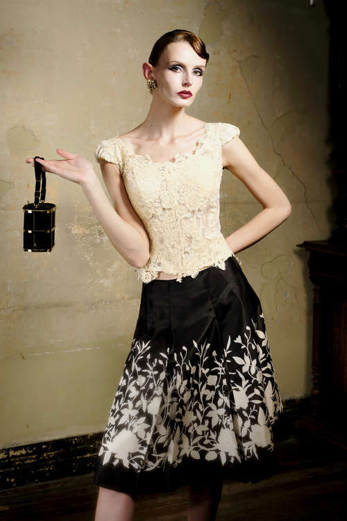 Black A-line pleated skirt with cream floral print at hem, front view