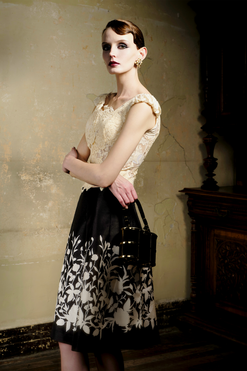 Black A-line pleated skirt with cream floral print at hem, front view