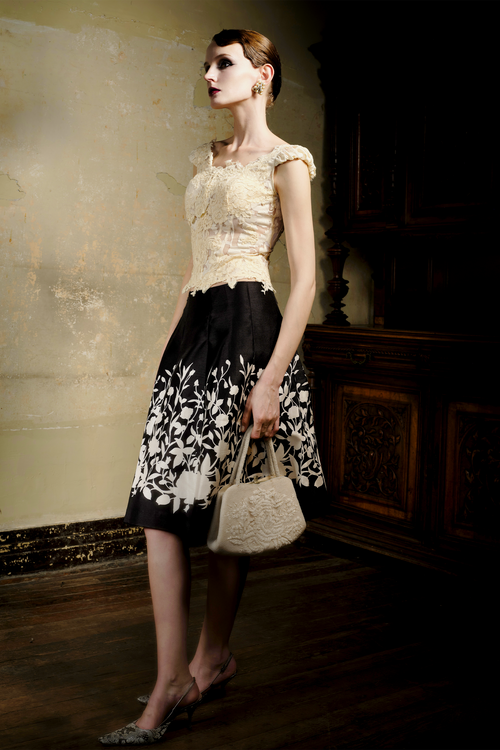 Black A-line pleated skirt with cream floral print at hem, front view