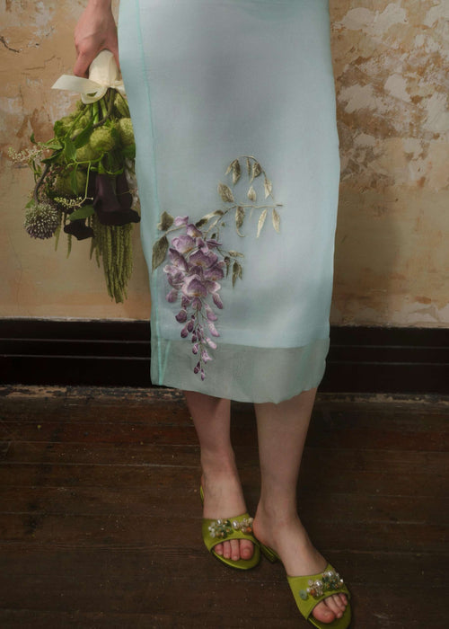 Close-up of the wisteria embroidery on the sheer layered hem of a mint silk organza midi skirt