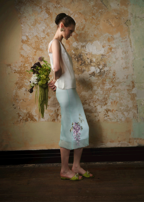 Side view of a mint green embroidered silk organza midi skirt showing the wisteria hem
